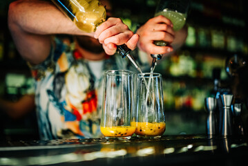 bartender making cocktail with passion fruit in a nightclub bar
