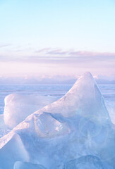 Winter landscape with ice hummocks glittering in the sun and mountains of Lake Baikal in Siberia at sunset. Natural background.