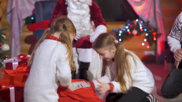 The girls receive a little kitten in a box as a gift from Santa Claus. Cheerful and happy family on Christmas holidays. Gift in a holiday box.