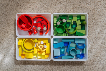Educational games for Colors sorting. Red, yellow, green and blue wooden blocks in boxes. Colors sorter toy. Learning through play. Developing Montessori toddlers activities.