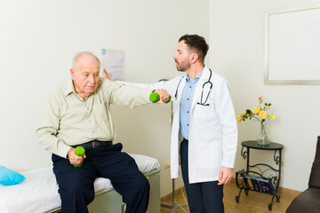 Fototapeta premium Old man in his 80s using dumbbells for a medical check up