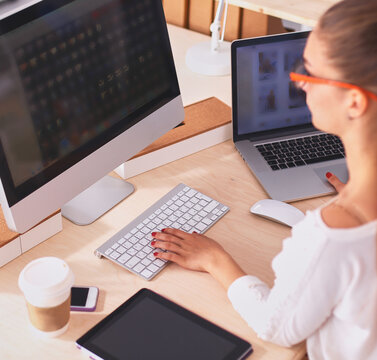 Young woman working in office, sitting at desk