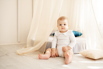 cute little baby boy or girl in a bright children's room with a wigwam in a white cotton bodysuit