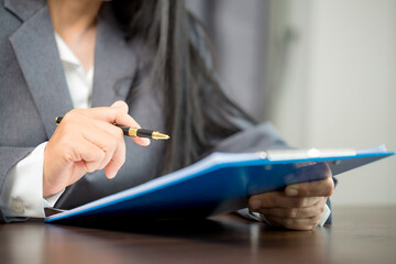 Workplace closeup person professional businesswoman sitting at desk hold pen signing or signature contract paper. Employee woman writing agreement document on paperwork form corporate at work office