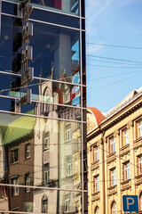 A transparent building in the middle of the city center with many windows and other buildings next...