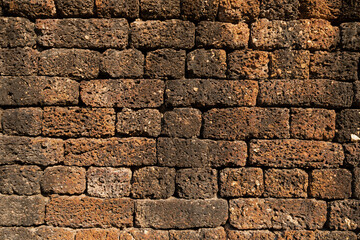 Textured background of a wall of irregular stones of reddish ochre colors, in one of the temples of Sukhothai Historical Park