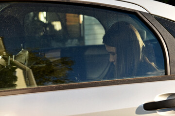 The girl sitting in the car behind the glass