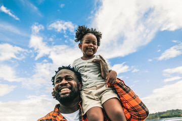 Father and daughter enjoying themself outdoor. His daughter is sitting on this shoulder.