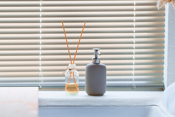 Glass jar with wooden aroma sticks and a bottle of liquid soap in the bathroom