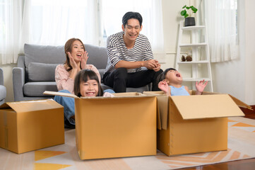 Asian family husband and wife and children with cardboard boxes having fun on moving day, Mortgage, loan, property and insurance concept.