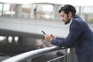 Confident businessman with formal suit using smart phone, smiling, talking and checking email.