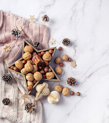 Christmas star with nuts, cones, cinnamon,  Decorations and knit sweater on marble background. Christmas holiday concept. festive winter season. flat lay. copy space