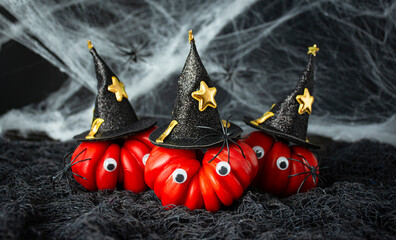 Halloween food.Red tomatoes in witch hats with spiders on a dark background. Halloween background. Copy space.