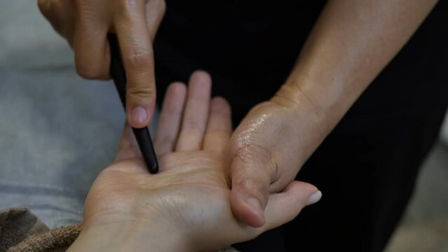 the process of acupressure of the palm of the hand close-up with the help of Teynshine by pressing on the points of the inner side of the palm. Thai or Korean hand massage reflexology