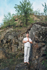 a young guy meditates while standing near a rock. The concept of meditation, dreams, well-being and healthy lifestyle.