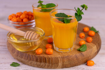 Sea buckthorn juice with honey and mint on a wooden board.
