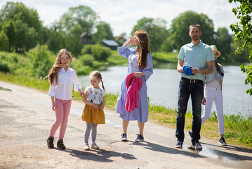 Happy young family- mother,father and three children daughter girls walking on city sidewalk