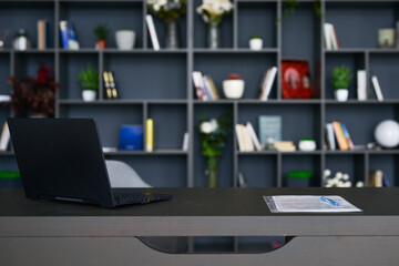 Table with laptop in home office interior.