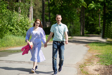 Fototapeta premium young family, married couple, man and woman walking in the park on a sunny summer day