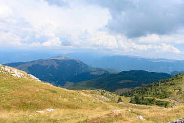 Beautiful mountain landscape seen from the top of Monte Baldo, close to the Garda lake, Italy. There is a lot of mountains, and a lot of forrests on the hill tops. It is a beautiful sunny summer day