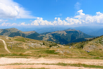 Fototapeta na wymiar Beautiful mountain landscape seen from the top of Monte Baldo, close to the Garda lake, Italy. There is a lot of mountains, and a lot of forrests on the hill tops. It is a beautiful sunny summer day