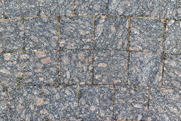 The texture of the sidewalk paved with stone, which can be used as a background. The texture of the stone.