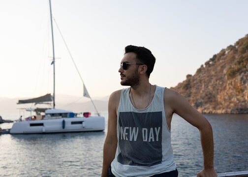 Young, handsome man with sun glasses on sailing boat. Summer vacation, rich holiday concept. 