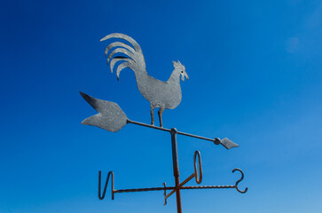Un anemoscopio a forma di gallo si staglia su un cielo azzurro con la banderuola che indica la direzione del vento