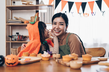 Young girl and mother at Halloween making treats and cupcake on table. Happy Halloween day