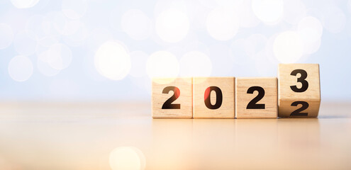 Flipping of wooden block cube to change 2022 to 2023 with bokeh for merry Christmas and happy new...