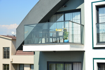 Moderner Balkon mit Sturzschutz/Sichtschutz aus Glasplatten und Metall-Geländer an einer Neubau-Hausfront