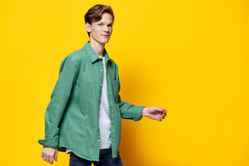 guy in a green shirt posing with his hand raised to the side on a yellow background