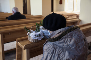 Woman praying in the church on Easter Eve with a basket with sacred food.