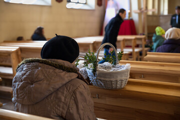 Woman praying in the church on Easter Eve with a basket with sacred food.