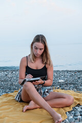 Fototapeta na wymiar Workplace sea.Remote work.Girl freelancer works remotely on the seashore.workation, remote work,WFVH,Van Life vibes work from vacation home,work travel,remotely work.Travelling