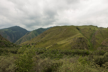 Dramatic landscape - beautiful hillsides and a picturesque valley against a background of cloudy sky and foggy haze and space to copy