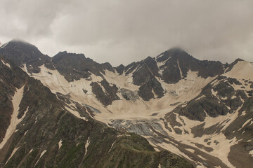 Dramatic landscape - peaks of the high Caucasus mountains and white snow on the peaks on a cloudy day in kabardino-balkaria in Russia and copy space