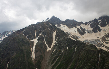 Dramatic landscape - peaks of the high Caucasus mountains and white snow on the peaks on a cloudy day in kabardino-balkaria in Russia and copy space