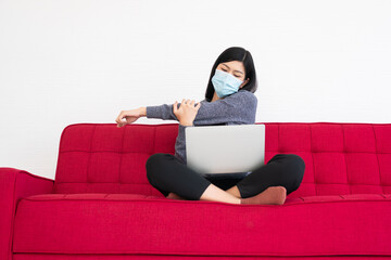 Tired woman wearing a face mask,  pain in neck tensed muscles and stretch, the suffering of office syndrome after long hours work on the computer. Office syndrome and Health care concept.