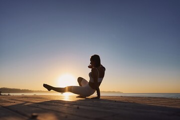Silhouette young woman practicing yoga on the beach. Caucasian girl exercising yoga in nature, morning at seashore