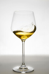 White wine glass on gray background. Moving liquid, splash and swirl.