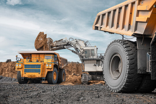 Large quarry dump truck and excavator. Big mining truck work coal deposit. Loading coal into body truck. Production useful minerals. Mining mining machinery to transport coal from open-pit production