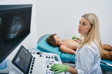 Heart ultrasound exam for male child with ultrasound specialist while medical exam at pediatrics