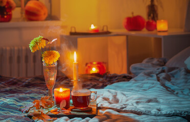 cup of tea and  chrysanthemum in vase with burning candles in bedroom