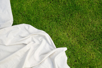 white picnic blanket on green grass background, top view