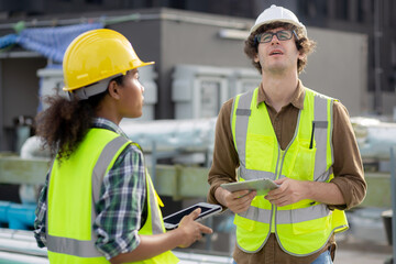 Young man and woman is architect planning and inspector project and looking digital tablet at construction site, engineer male and female working and examining for development real estate.