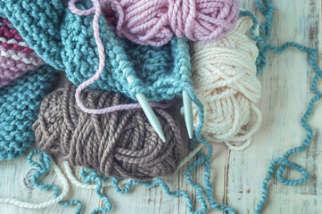 Skeins of thread and knitting needles on wooden background, selective focus.