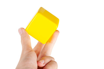 Hand holding up a simple plain yellow floating hovering cube element or node grabbing it between...