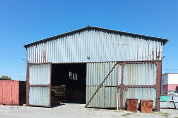 Fototapeta na wymiar Industrial old metal hangar. Summer against the blue sky.