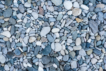 Small grey pebbles cover sea beach for visitors and tourists to relax and spend vacation. Pebble beach difficult for people to walk